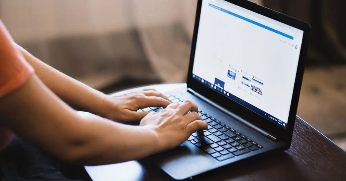 Close-up of person typing on a laptop indoors, showcasing technology use.