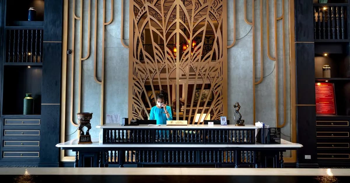 Luxurious hotel reception area with intricate design and a female receptionist at work.