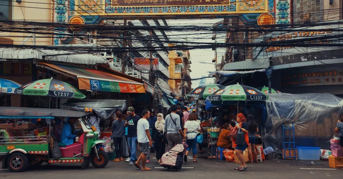 A lively street market bustling with vendors and pedestrians under colorful signage.