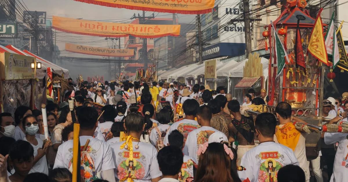 A lively street parade in Thailand showcasing traditional costumes and cultural banners.