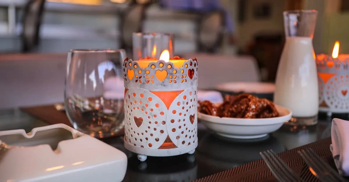 Cozy indoor table setup featuring decorative candles, snacks, and drinks, creating a warm ambiance.