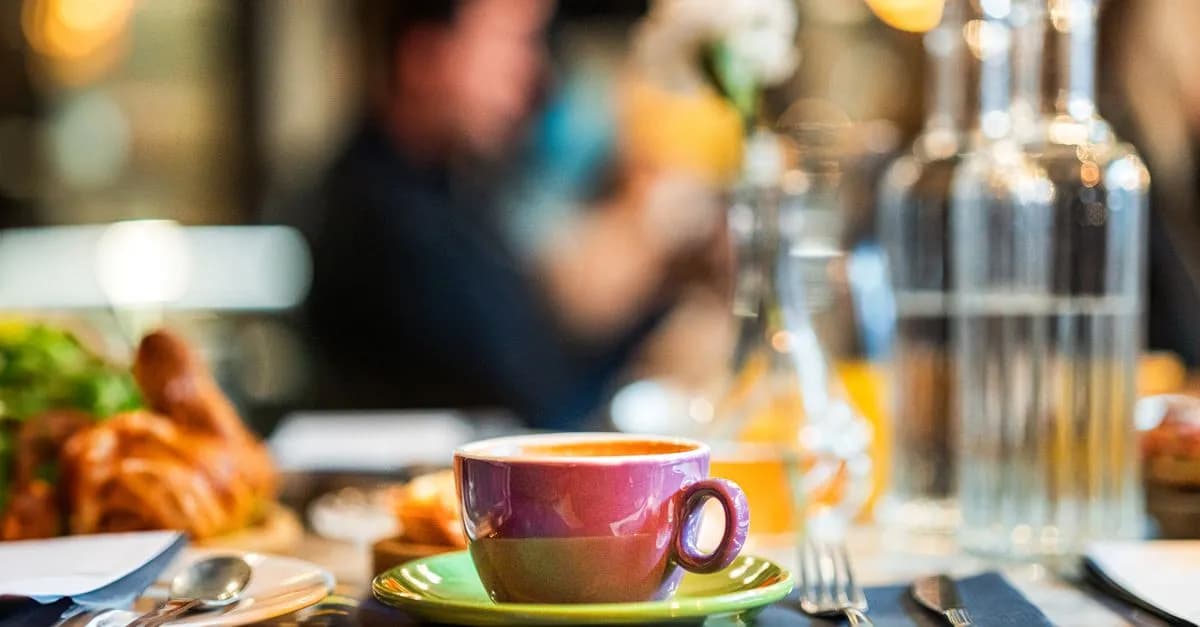 A vibrant cafe setting featuring a colorful coffee cup and breakfast items on a table.