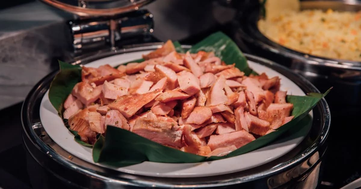 Plate of sliced smoked ham on a buffet, perfect for events and catering.