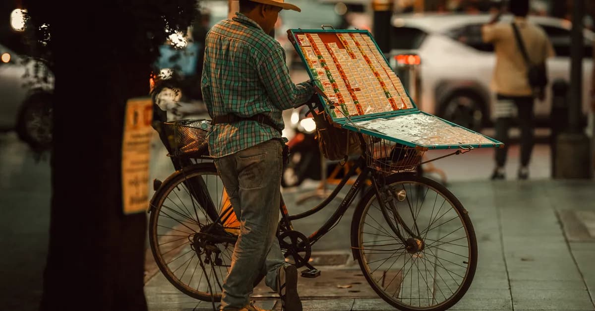 Street vendor in Bangkok with a bicycle selling lottery tickets in the evening.