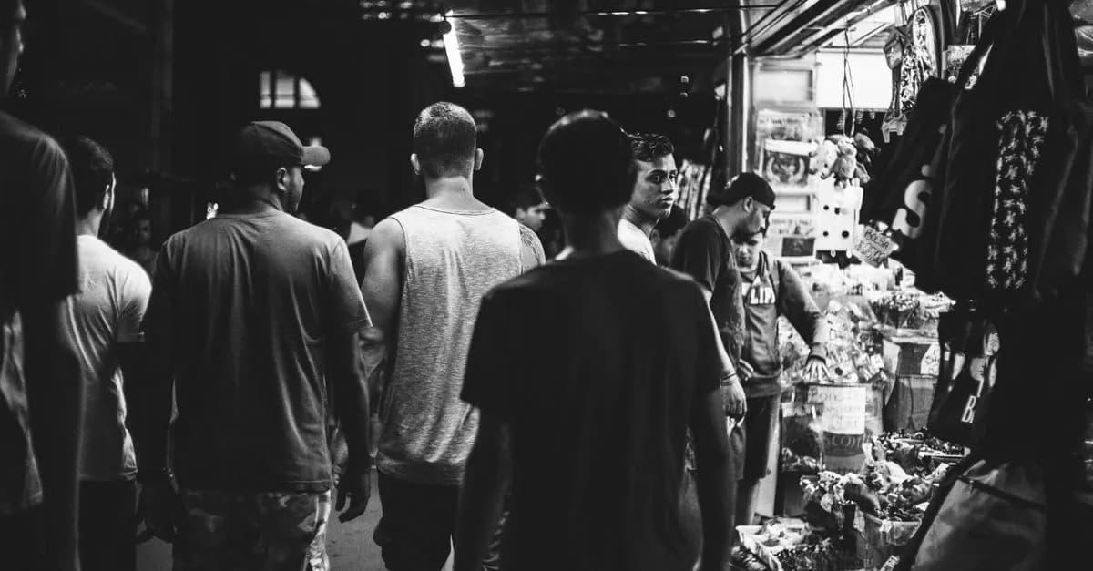 A bustling night market scene captured in black and white, showcasing shoppers and vibrant stalls.