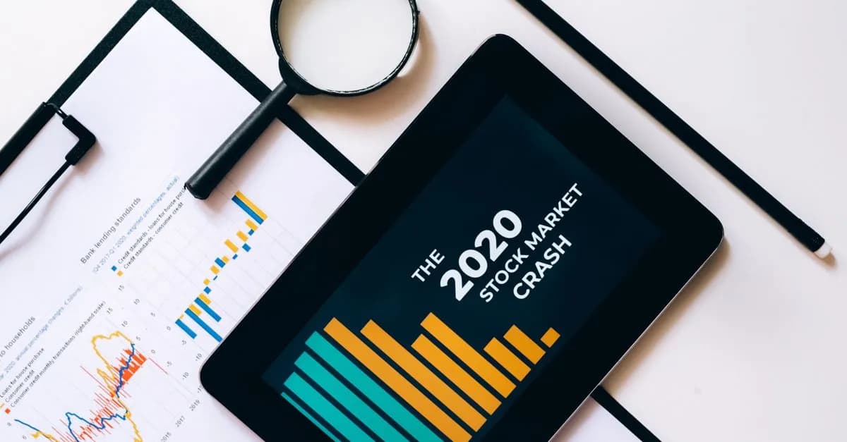 Magnifying glass and tablet analyze 2020 stock market crash data with charts on clipboard.