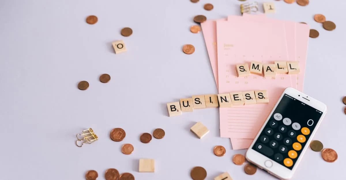 Flat lay image of small business finance concept with coins, calendar, and smartphone calculator.